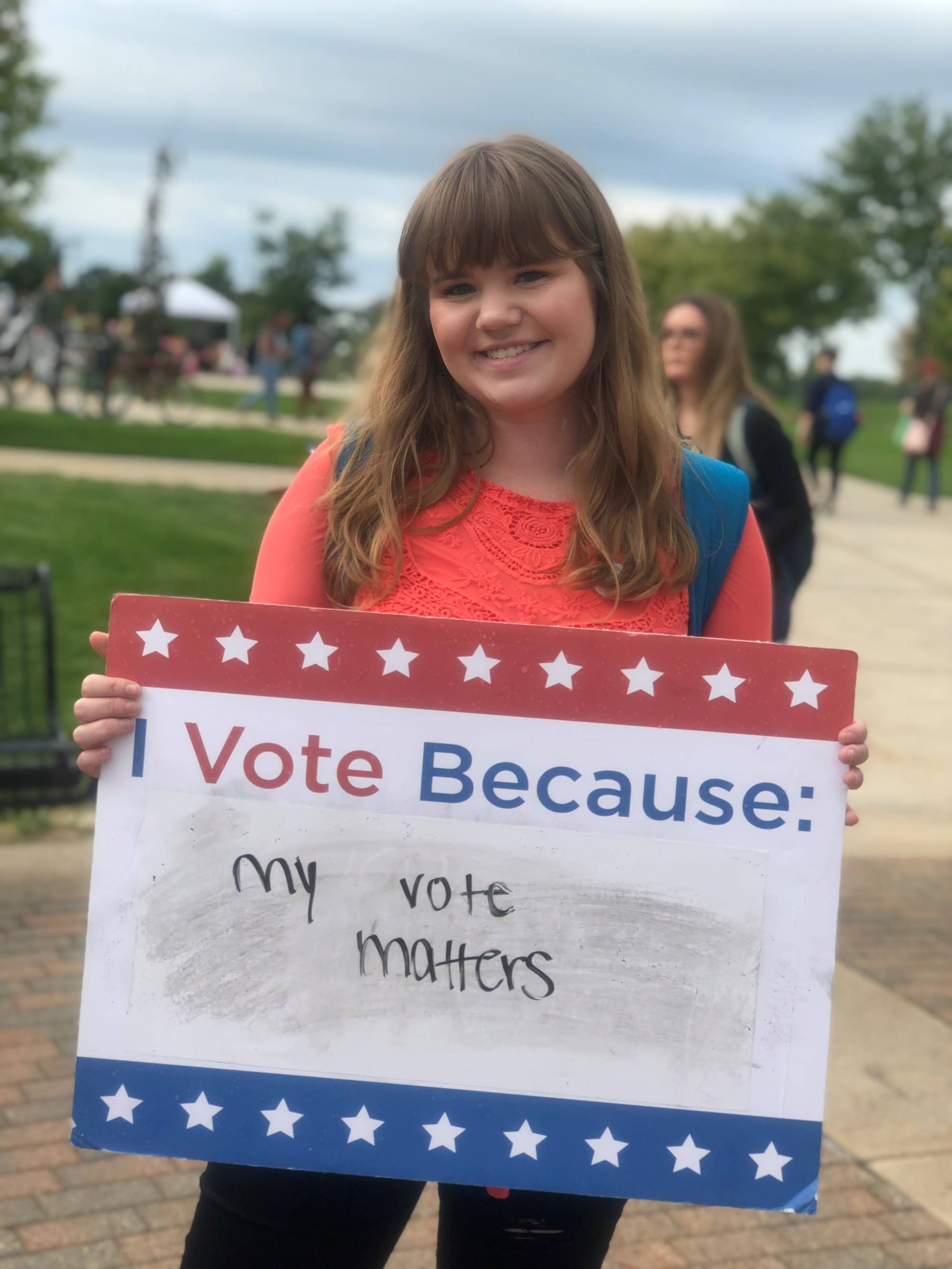 Student holding sign titled "I vote because: My vote matters"